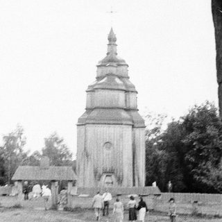 Traditional wooden church tower with people around.