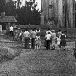 Traditional wooden church with people walking towards it.