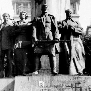 Statue defaced with graffiti, depicting Soviet leaders.