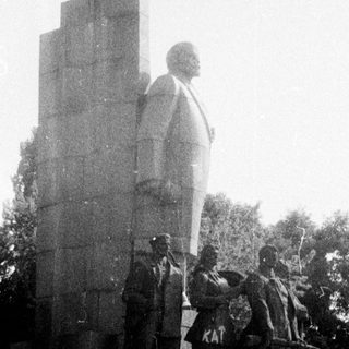 Statue of Lenin with revolutionary figures on pedestal.