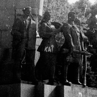 Statue of Lenin with revolutionary figures on pedestal.