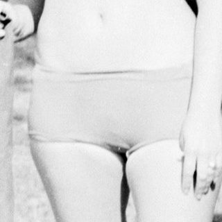 Young woman posing outdoors in vintage swimsuit.