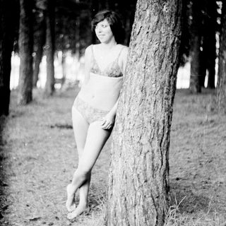 Woman standing against tree in outdoor setting.