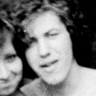 Three shirtless children posing together outdoors in a forest.