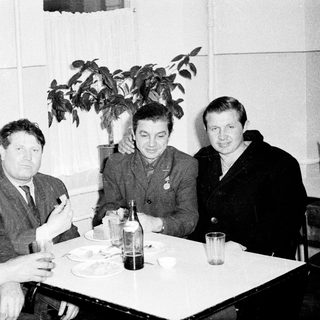 Four men in formal attire dining together indoors.