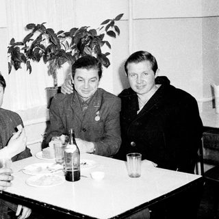 Four men in formal attire dining together indoors.