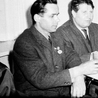 Four men in formal attire dining indoors, mid-20th century.