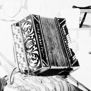 Person playing large accordion indoors.