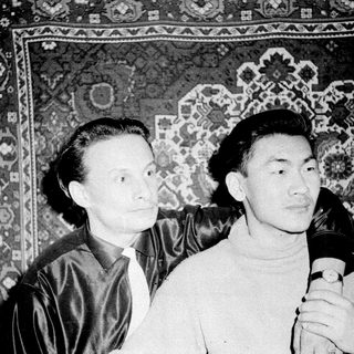 Two men in vintage attire posing indoors.
