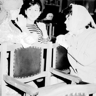 Costumed women and girl in vintage church pews.