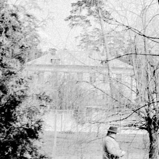 Vintage photo of solitary figure walking in snow-covered park.