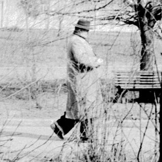 Vintage photo of solitary figure walking in snow-covered park.