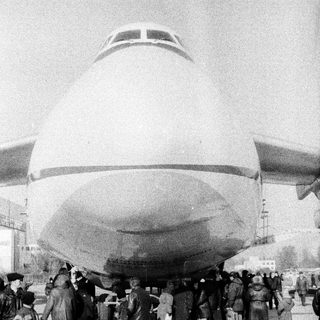 Large airship with crowd of people underneath.