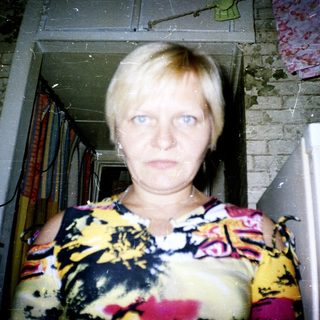 Woman standing in doorway with floral top.