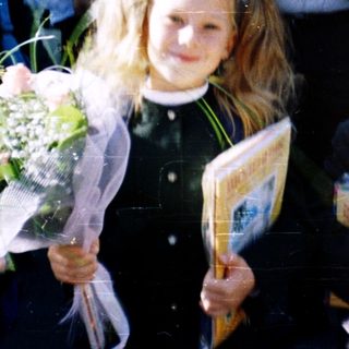 First-day-of-school celebration with students in traditional attire holding flowers.