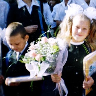 First-day-of-school celebration with students in traditional attire holding flowers.