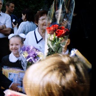 First-day-of-school celebration with students in traditional attire holding flowers.