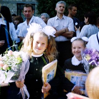 First-day-of-school celebration with students in traditional attire holding flowers.