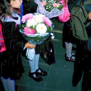 First-day-of-school celebration with students in formal attire holding flowers.