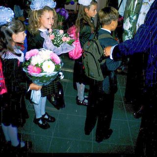 First-day-of-school celebration with students in formal attire holding flowers.