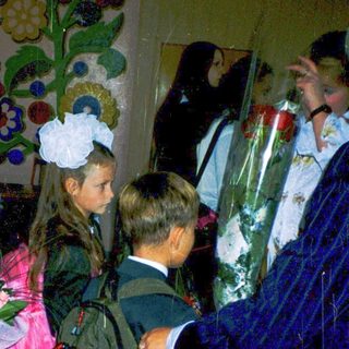 First-day-of-school celebration with students in formal attire holding flowers.