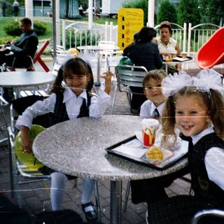 Children in school uniforms eating outdoors at McDonald's.