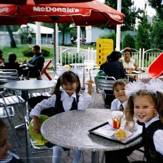 Children in school uniforms eating outdoors at McDonald's.