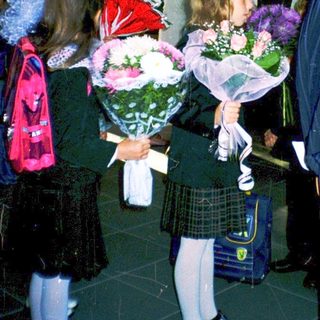 First-day-of-school ceremony with students holding flowers.