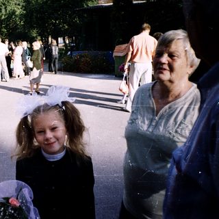 A young girl in a princess dress walks outdoors with an elderly woman.