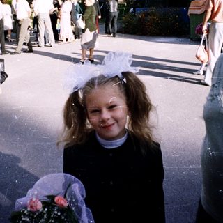 A young girl in a princess dress walks outdoors with an elderly woman.