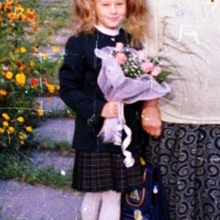 A woman and young girl holding flowers in a garden.