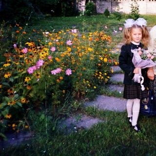 A woman and young girl holding flowers in a garden.