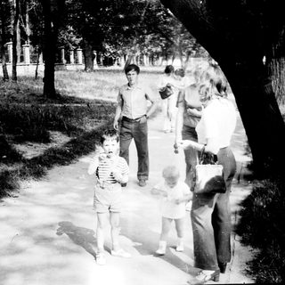 People walking and playing in a park at dusk.