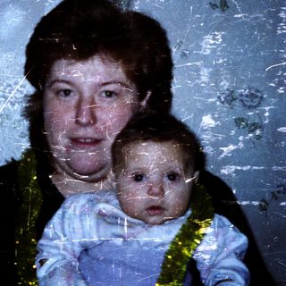 A woman holding a baby indoors.