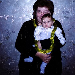 A woman holding a baby wearing a lei.