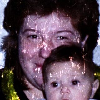A woman holding a baby wearing a lei.