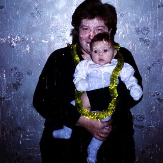 A woman holding a baby wearing a lei.