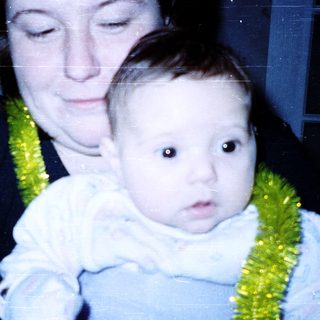 A woman holding a baby wearing a green floral bib.