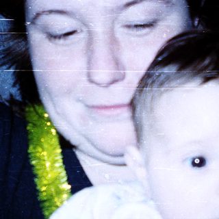 A woman holding a baby wearing a green floral bib.