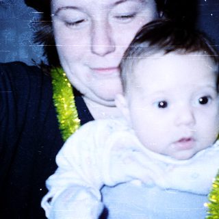 A woman holding a baby wearing a green floral bib.