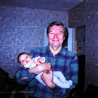 A man holding a baby indoors.