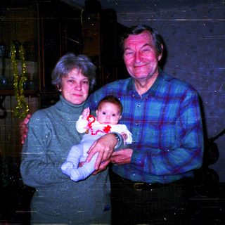 Family portrait with grandparents holding baby indoors.