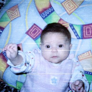 Baby in colorful play mat, reaching out.
