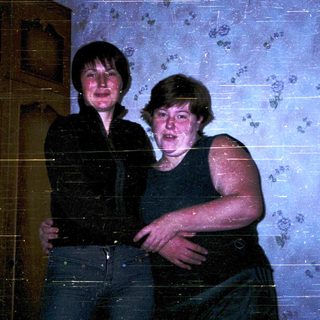 Two people posing indoors, wearing casual attire.