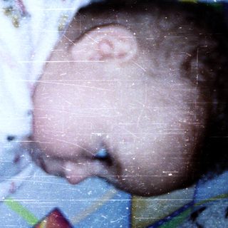 Baby wearing colorful pajamas, reaching up.