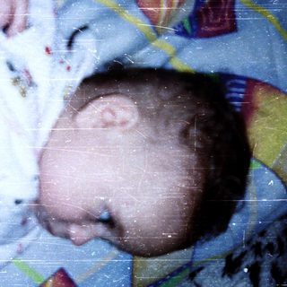Baby wearing colorful pajamas, reaching up.