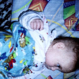 Baby wearing colorful pajamas, reaching up.