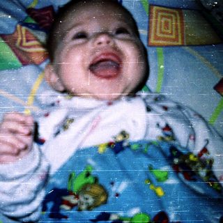 Baby laughing while holding toy.