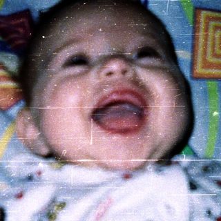 Baby laughing while holding toy.