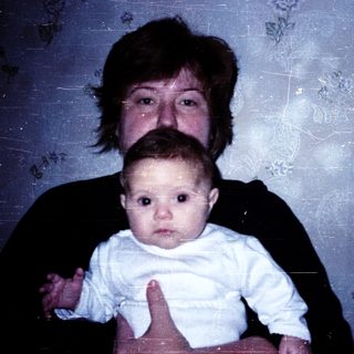 A woman holding a baby indoors.